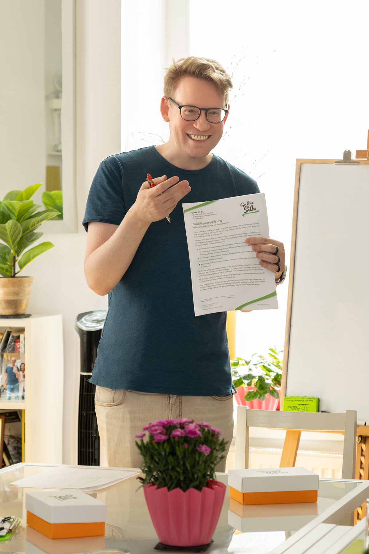 Michael En, lächelnd, hält ein beschriebenes Stück Papier in der Hand.